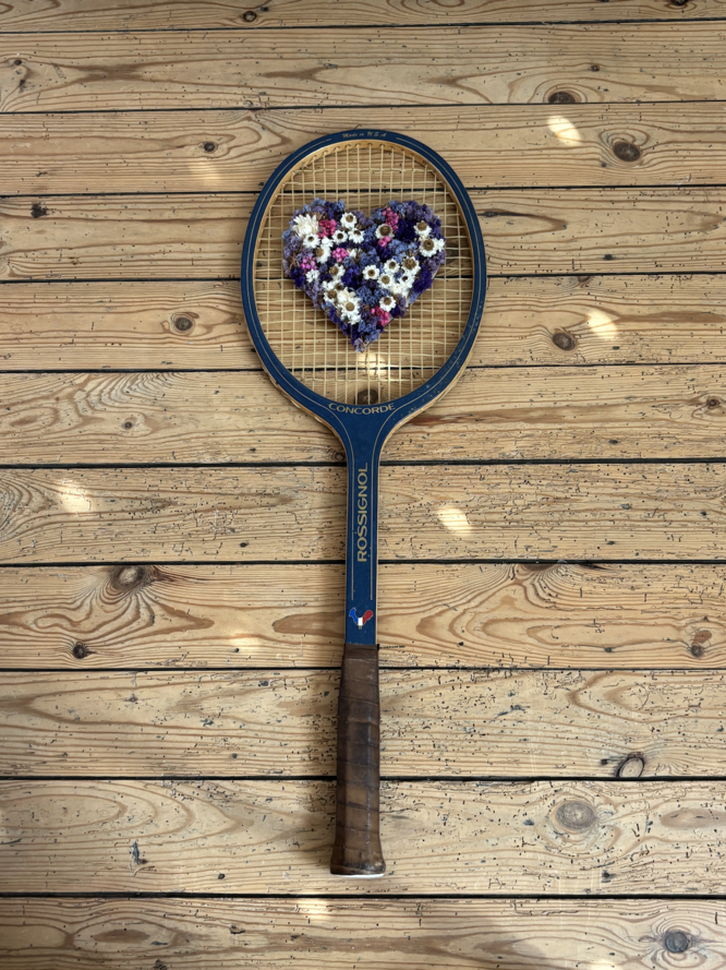 Raquette de tennis vintage en bois ornée d'un cœur composé de fleurs séchées naturelles dans des tons violets, blancs et crème